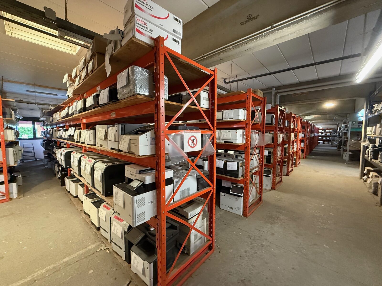 Warehouse aisle with orange shelving full of printers